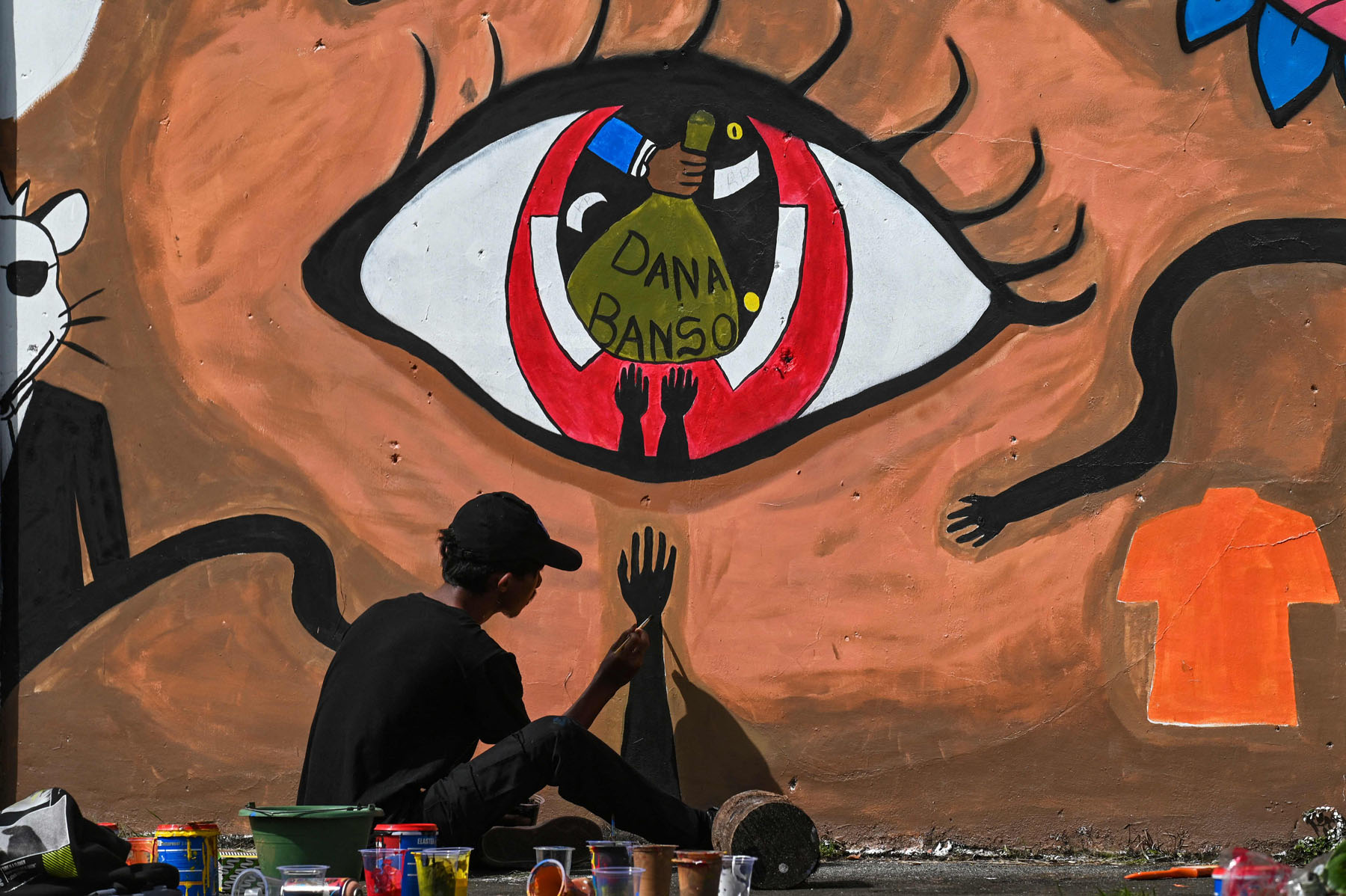A participant paints a wall during a mural festival ahead of commemorations for the 76th anniversary of the Indonesian police corps in Banda Aceh on June 18, 2022. (Photo by CHAIDEER MAHYUDDIN / AFP)