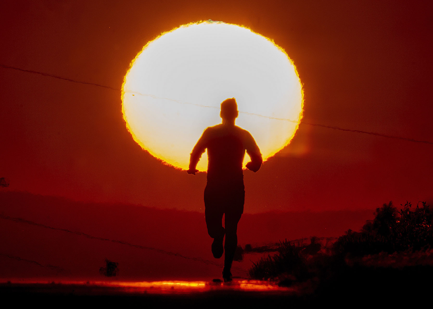 A man runs up a hill on a small road in Frankfurt, Germany as the sun rises on Friday, June 17, 2022. (AP Photo/Michael Probst)