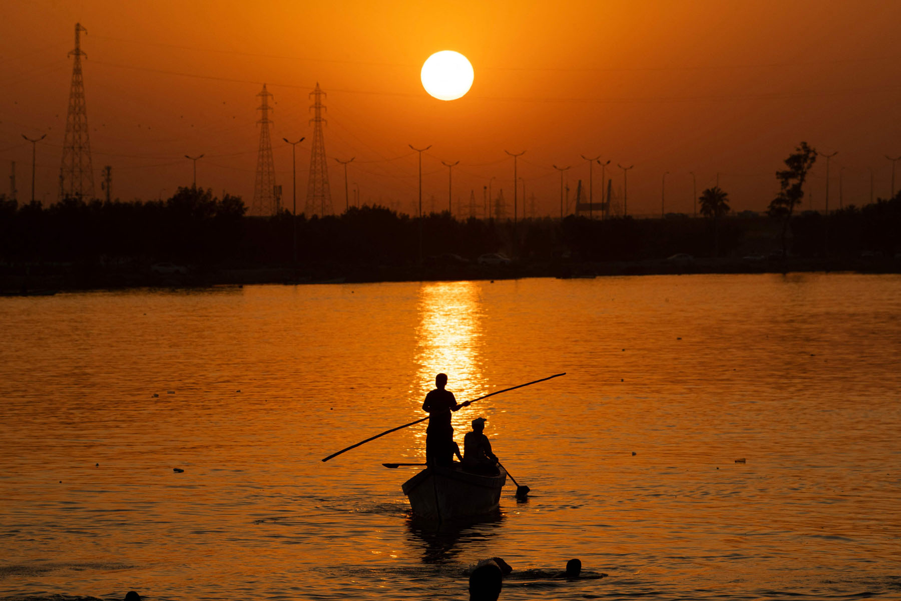 A man pilots a boat in the Shatt al-Arab waterway in Iraq's southern city of Basra near sunset on June 18, 2022. (Photo by Hussein Faleh / AFP)